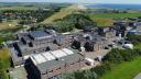 An aerial photo of the NIOZ building on Texel. You see an array of attached square buildings covered with solar panels, with a harbour in the background.